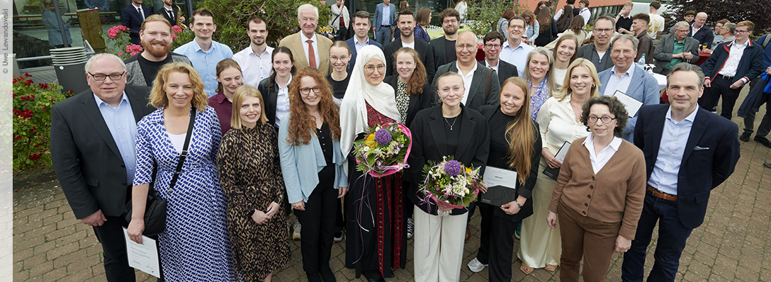 A group of people, two of them holding bouquets of flowers