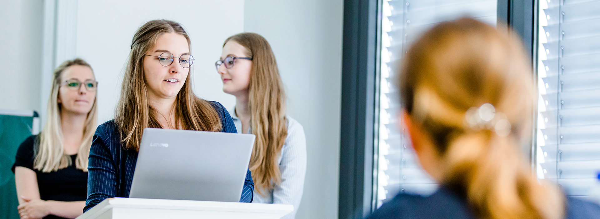 Drei Studentinnnen, eine schaut auf einen Laptop