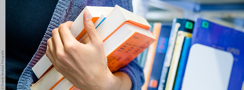 Studierende mit einem Stapel Bücher