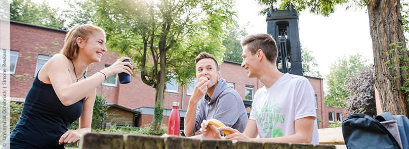 Studierende picknicken am Tisch im Garten